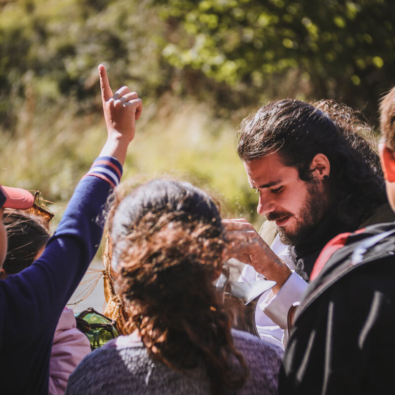 Enfants autour d'un jeune homme, l'un lève le doigt
