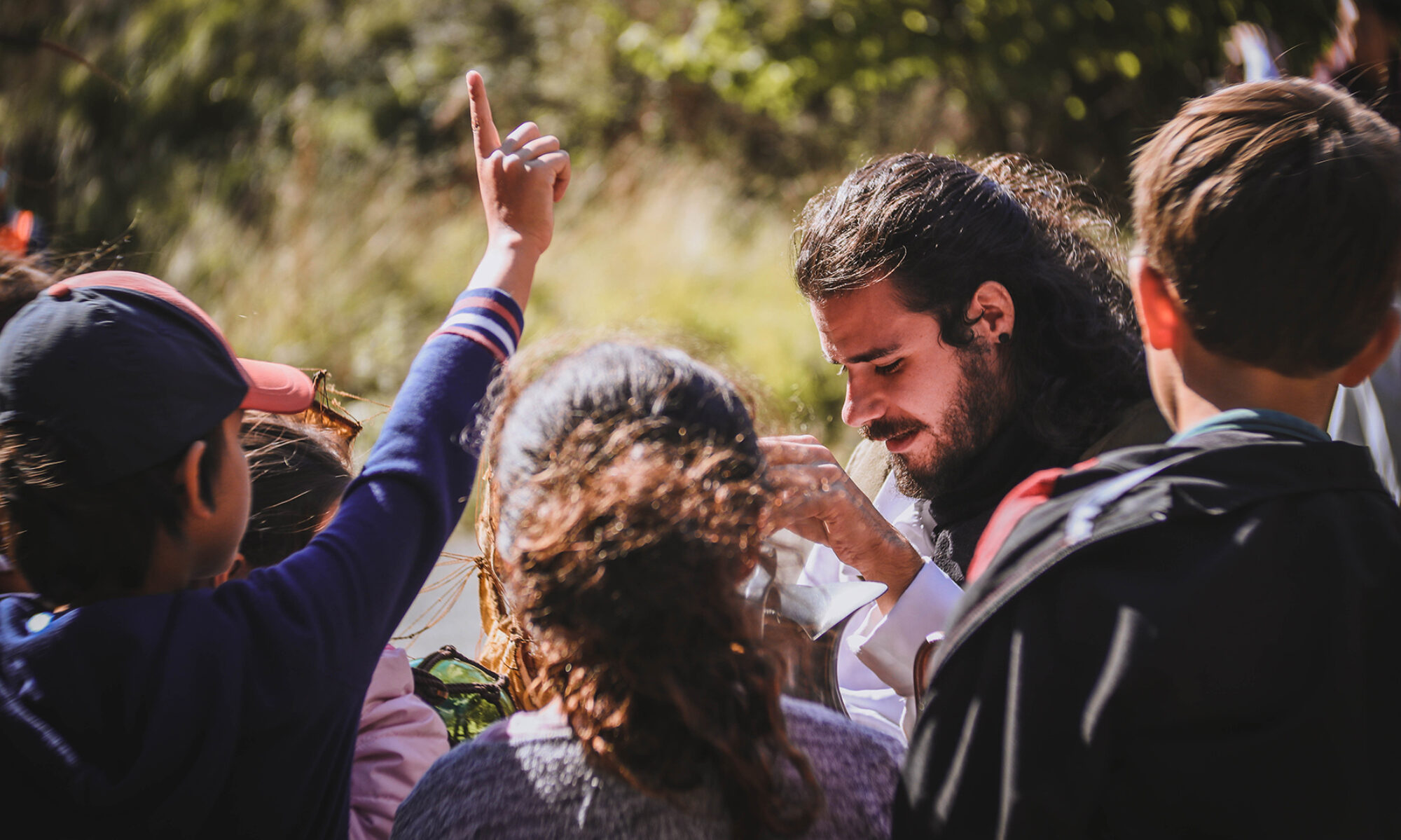 Enfants autour d'un jeune homme, l'un lève le doigt