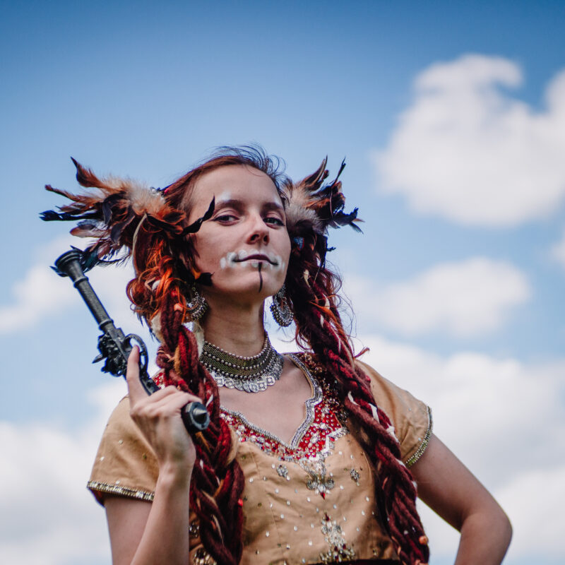 femme costumée en pirate avec des plumes, des longues tresses et un maquillage de squelette